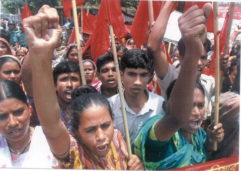 This is a close-up image of a group of people who are protesting. The women in front have arms raised, and many of the protesters are shouting.